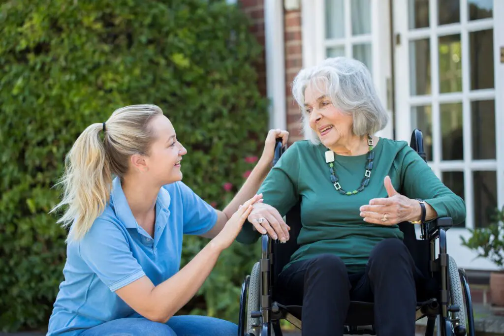 Caregiver and elderly woman in conversation outside.
