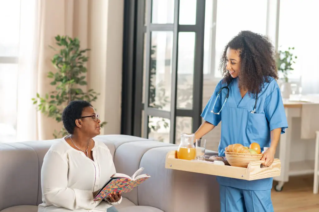 Nurse serving food to seated woman.