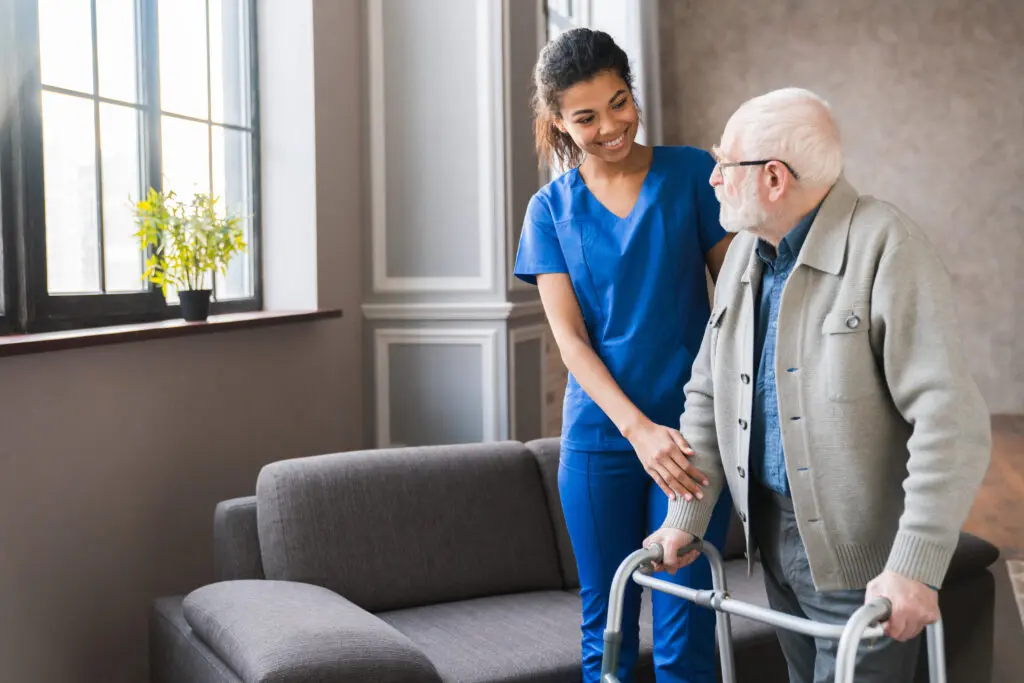 Caregiver assisting elderly man with walker.