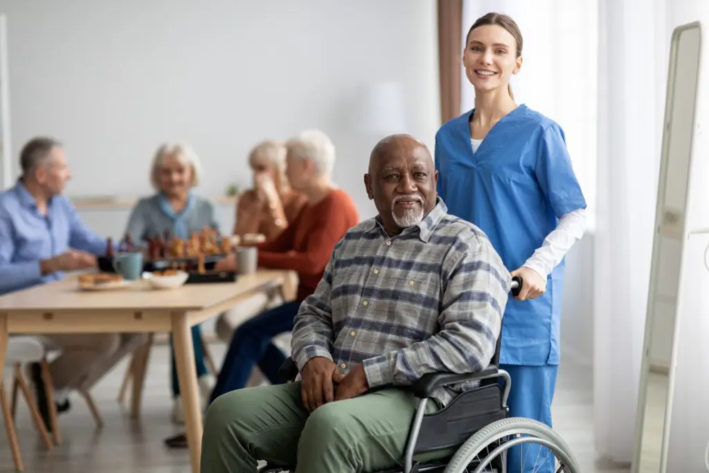 Caregiver with elderly man in wheelchair, smiling.