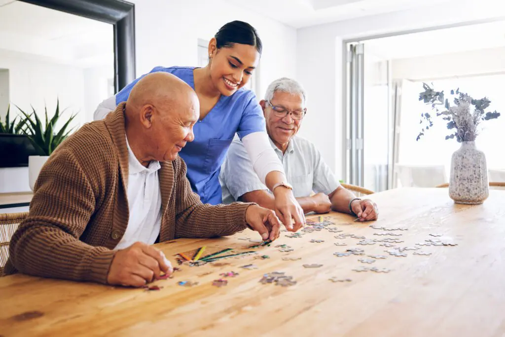 People assembling puzzle at a wooden table.