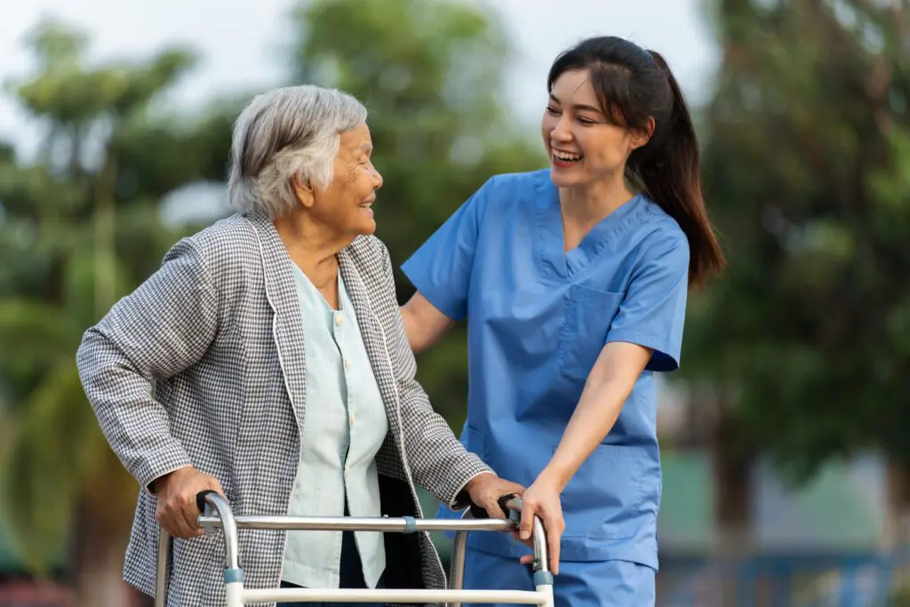 Elderly woman with walker, assisted by nurse.