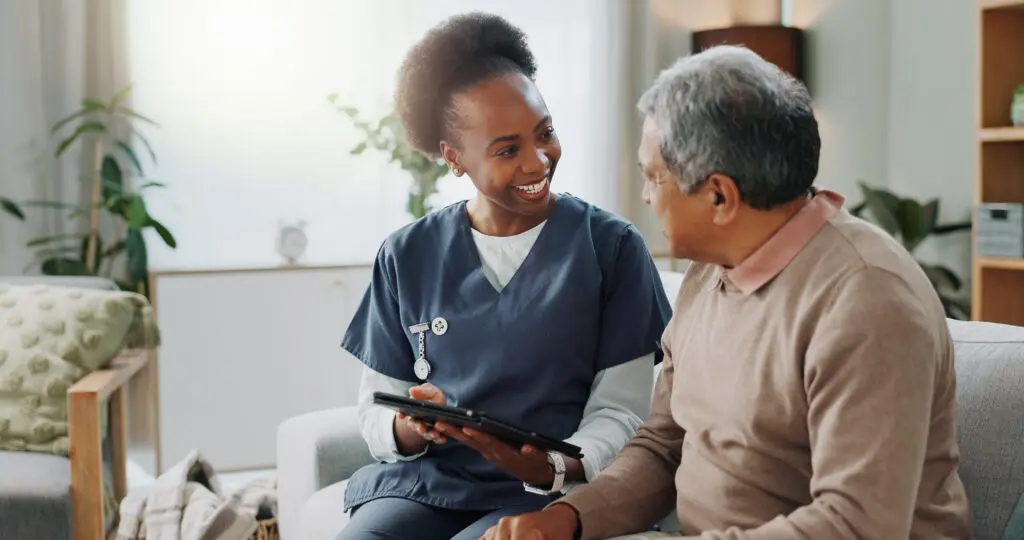 Nurse consulting with elderly man on sofa.