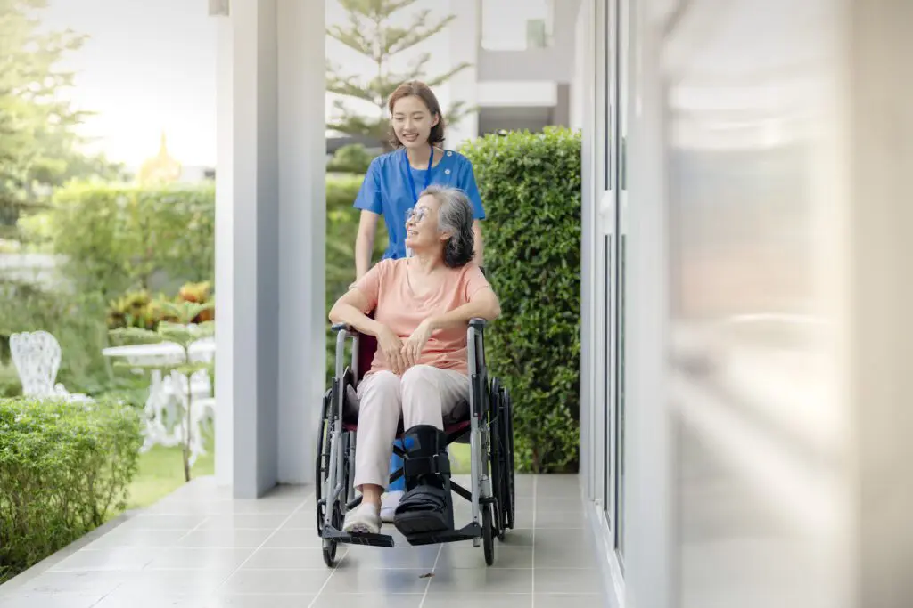 Young nurse pushing elderly woman in wheelchair