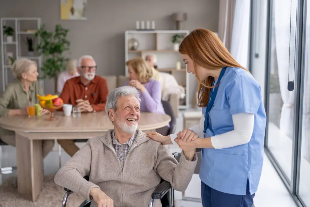 Elderly man in wheelchair with caregiver smiling.