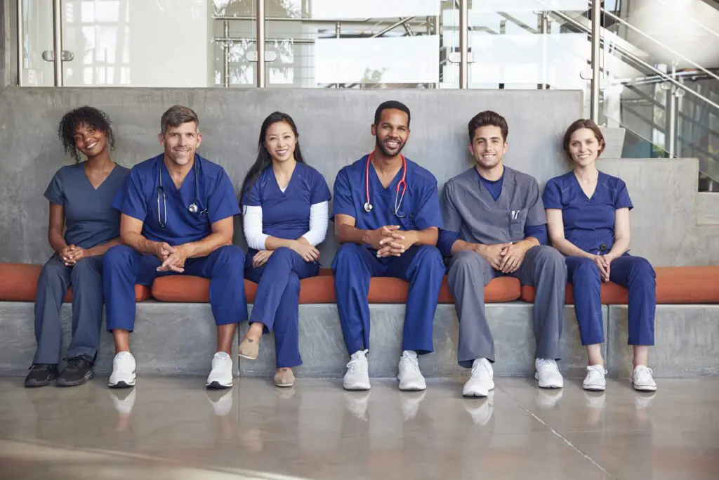 Healthcare professionals sitting together in scrubs.